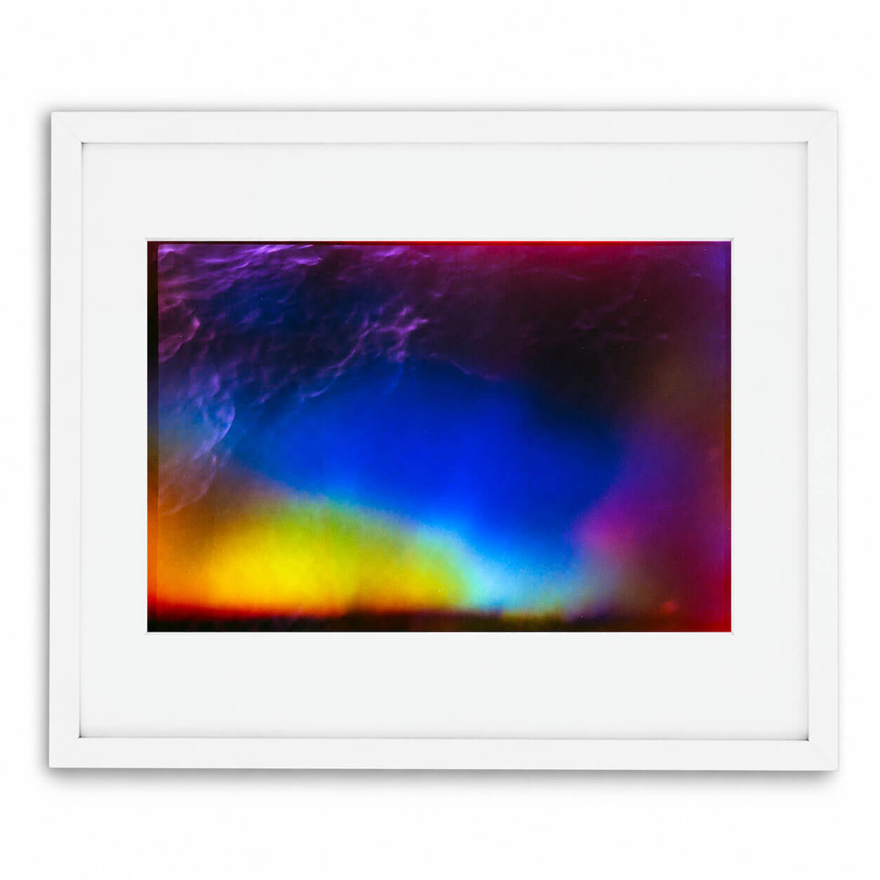 A framed abstract art print featuring a vibrant, colorful composition with a deep blue center, purple and magenta edges, and a bright yellow glow at the bottom, presented in a white frame with a white mat.